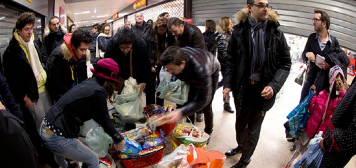 آرش درمبخش (راست ـ با شال‌گردن) در حال توزیع مواد غذایی باقی‌مانده از فروشگاه‌های بزرگ در بین مردم.