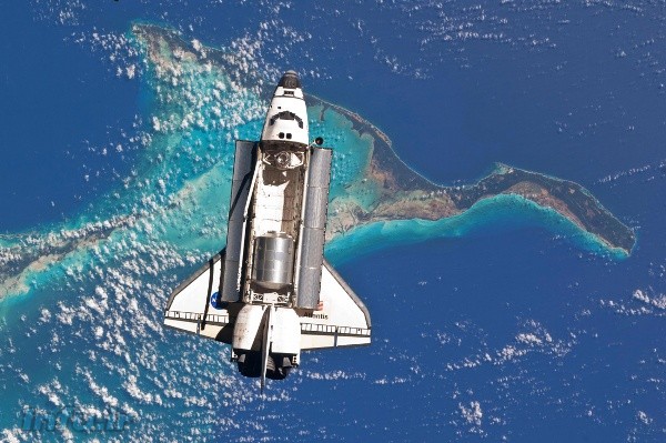 آتلانتیس، بر فراز سواحل باهاما از دریچه دوربین ران گاران. اتاقک لجستیکی چندمنظوره رافائلو در پایین، و گلوگاه اتصال آتلانتیس به ایستگاه هم در بالای محفظه بار آن به چشم میخورد.